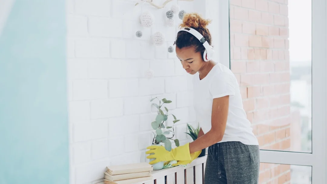 A cleaner in protective coveralls and gloves vacuuming a modern living room.